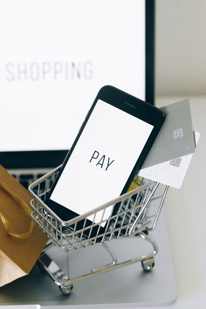 Smartphone in a miniature shopping cart symbolizes mobile shopping and online transactions.